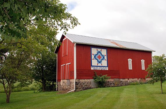 The freedom flicker barn quilt on the side of a red barn